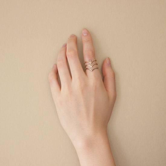 Model wearing Peak Band / Knife Edge in 14k yellow gold, Peak Band / Knife Edge in 14k white gold, and the Peak Ring on index finger